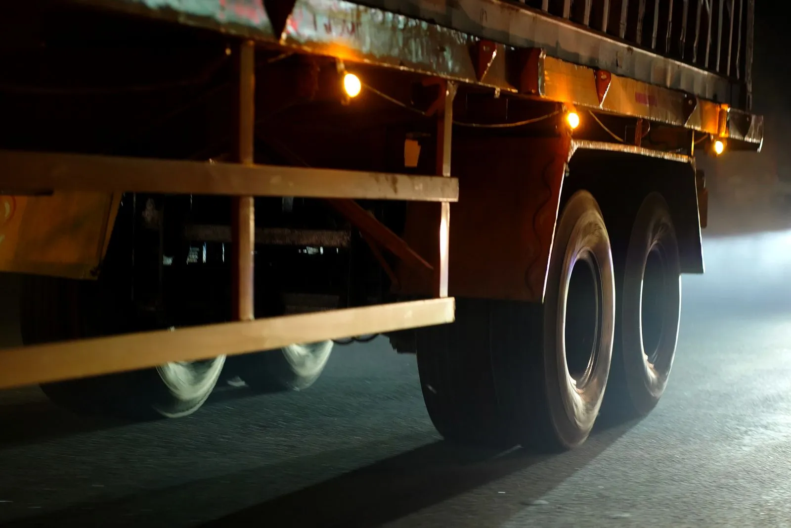 Dynamic close-up of truck wheels moving on an Indian road at night.